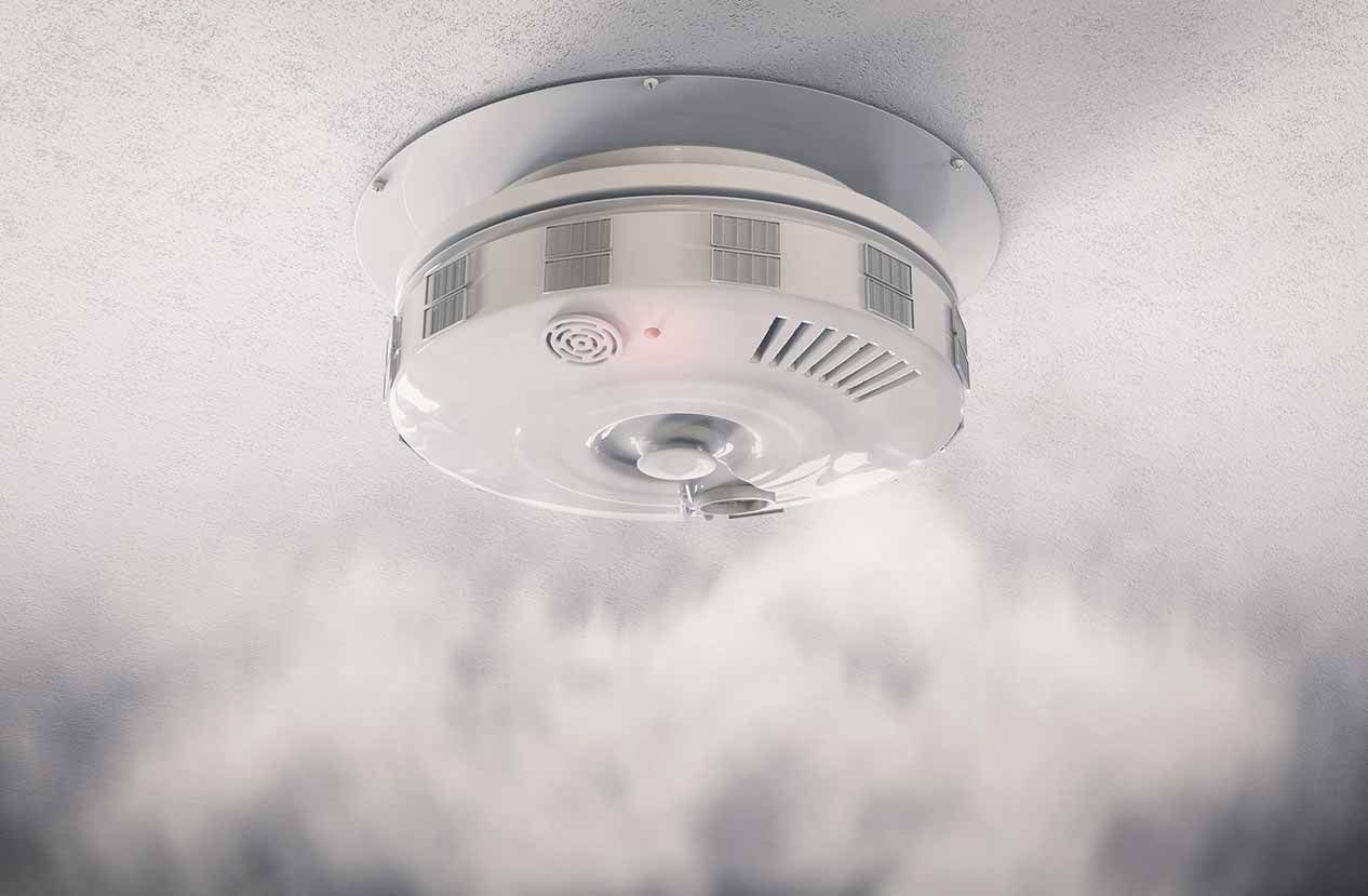 Un detector de humo cuelga del techo y sale humo de él.
