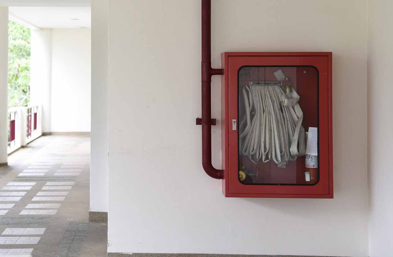 Una boca de incendios roja está colgada en una pared blanca en un pasillo.