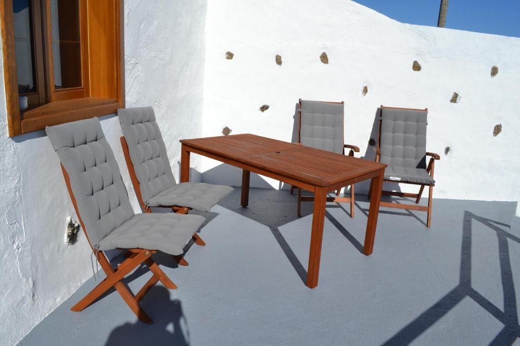 Un patio con una mesa y sillas frente a una pared blanca.
