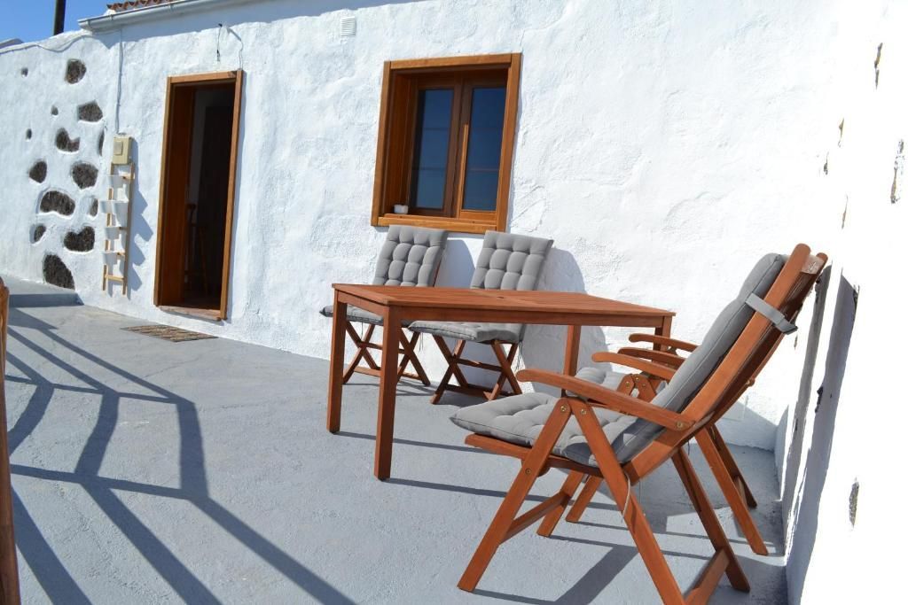 Un patio con una mesa y sillas frente a un edificio blanco.