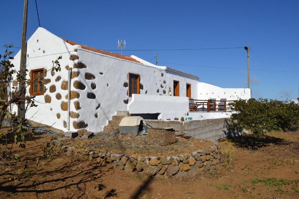 Una casa blanca con techo rojo está situada en medio de un campo de tierra.