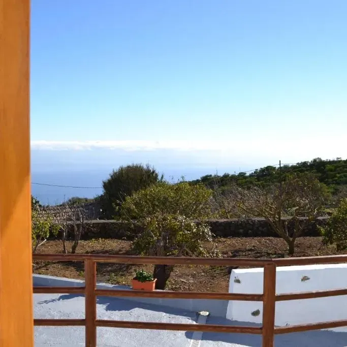 Una vista del océano desde un balcón con barandilla de madera.