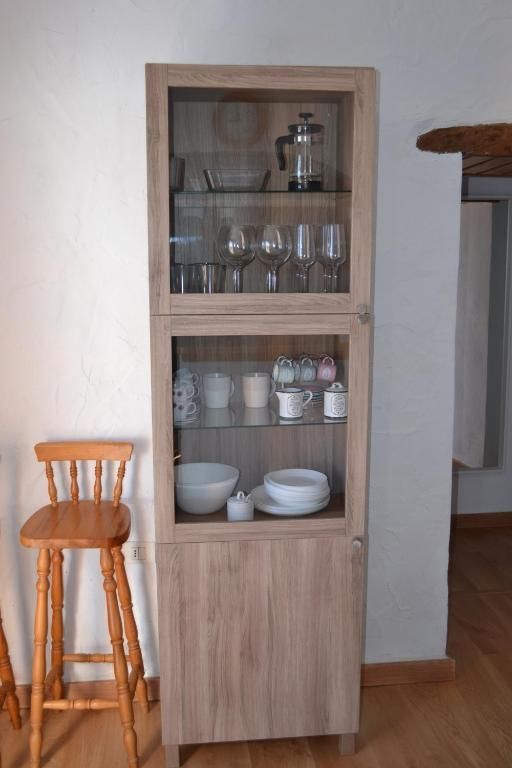 Un armario de madera con puerta de cristal lleno de platos y vasos.