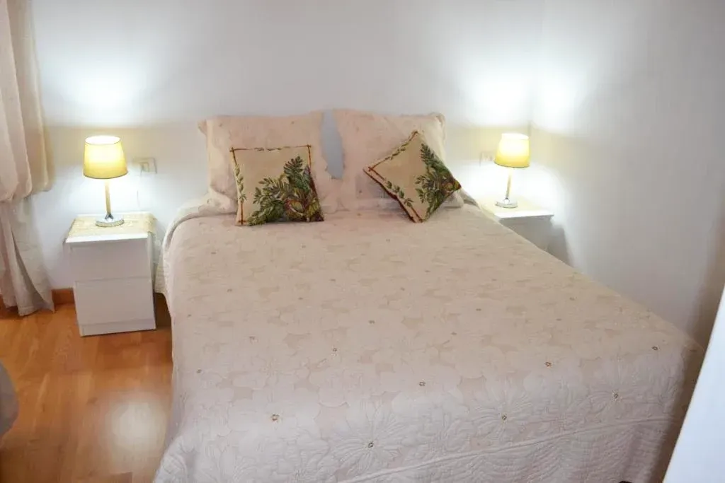 Un dormitorio con una cama, dos mesitas de noche y dos lámparas.