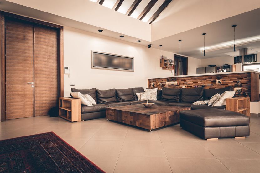 Salon confortable avec un canapé sectionnel marron, une table basse en bois et une grande porte en bois.