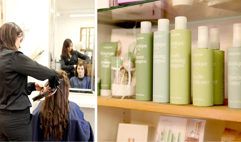 Friseursalon mit einer Stylistin, die an einer Kundin arbeitet; Regale mit grünen Haarprodukten im Vordergrund