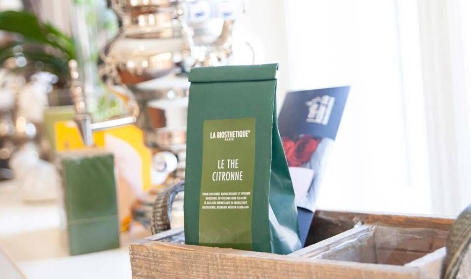 Eine grüne Hautpflegebox auf einem Tablett neben einer verschwommenen Flasche und einer Broschüre in einer hellen Präsentationsumgebung