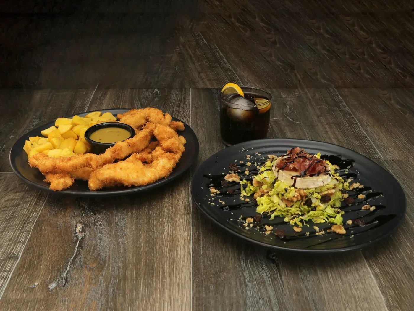 Dos platos de comida y una bebida sobre una mesa de madera. 