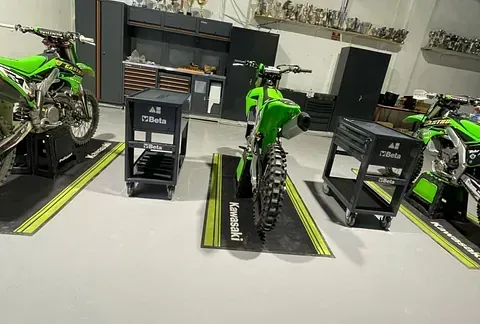 Una fila de motos de cross verdes están estacionadas en un garaje.