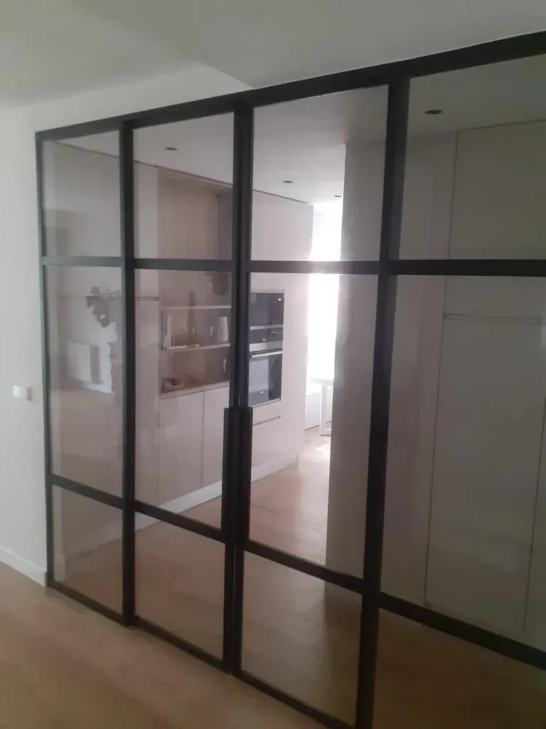 Una habitación con muchas puertas de cristal y una cocina al fondo.