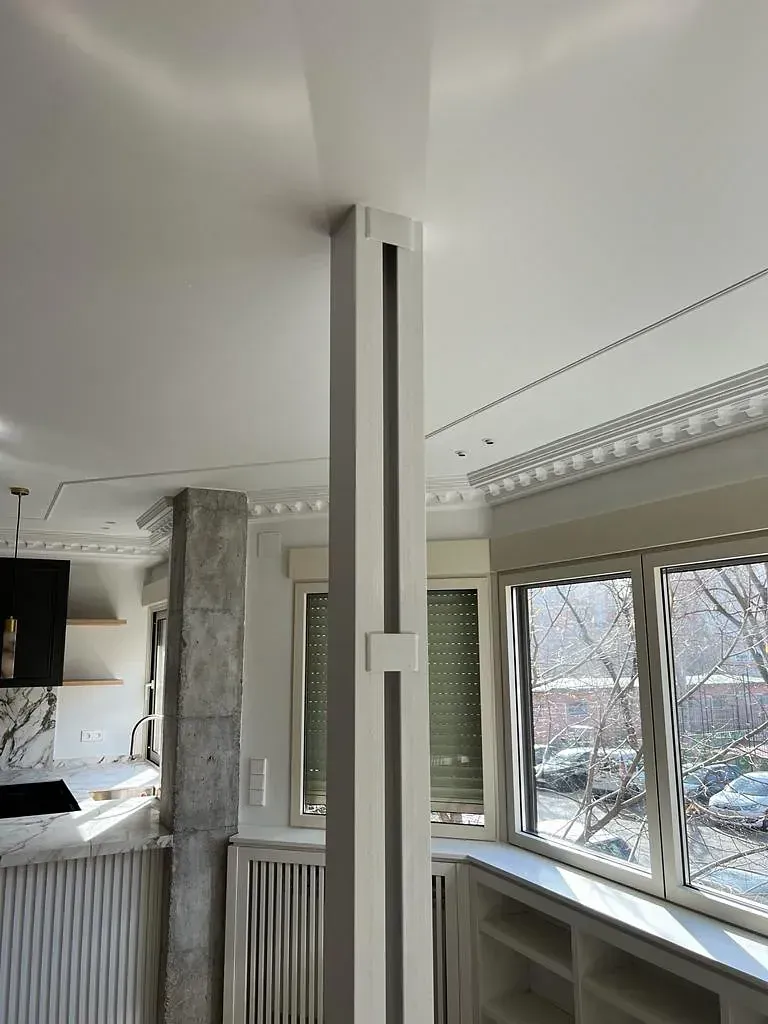 Una habitación con un pilar y muchas ventanas.