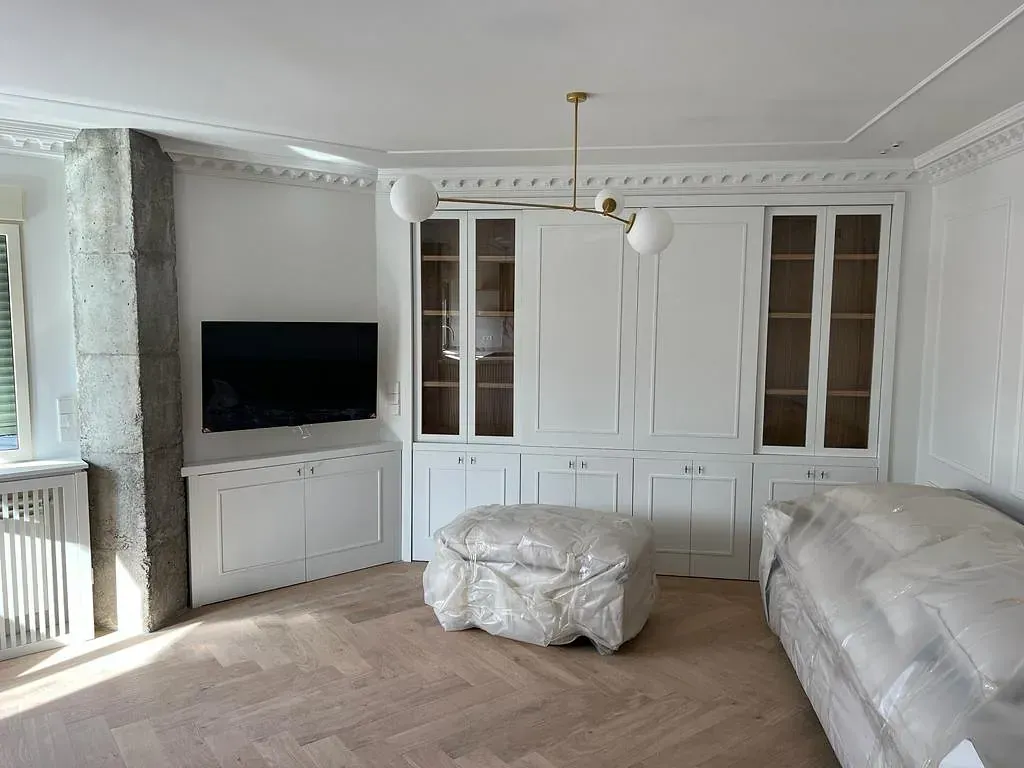 Una sala de estar con gabinetes blancos y un televisor de pantalla plana.