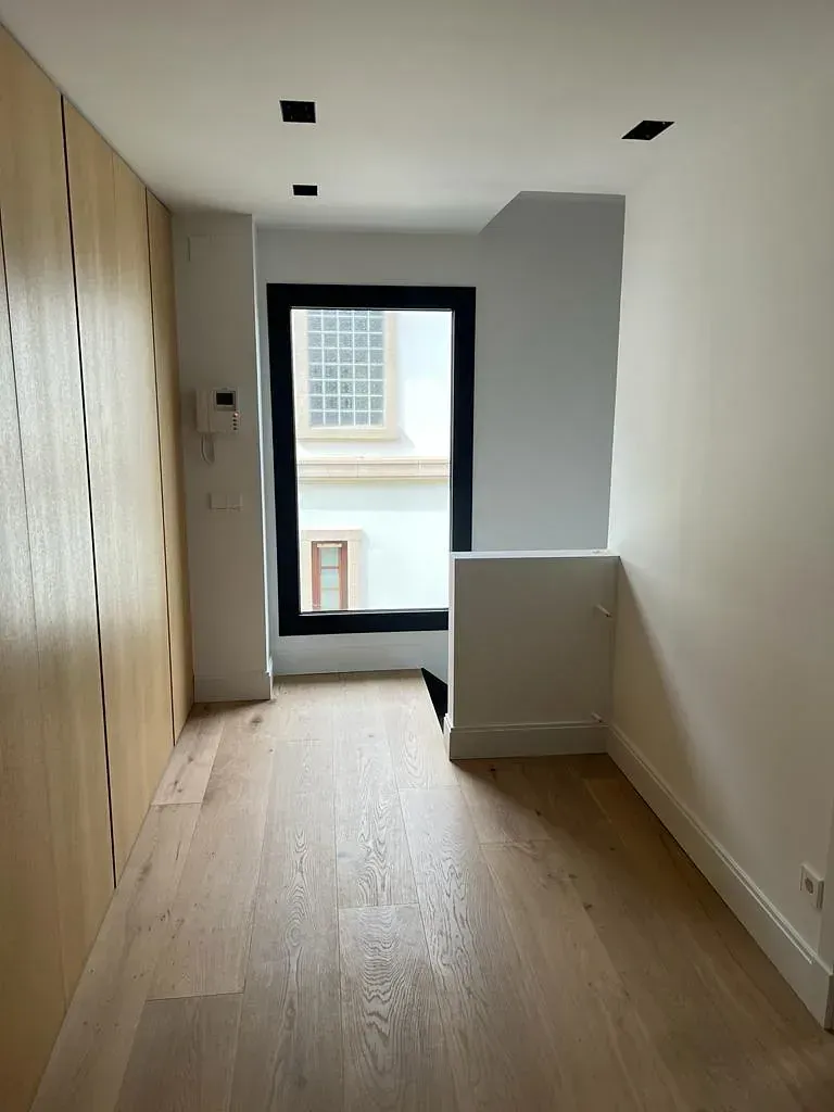 Una habitación vacía con pisos de madera y una ventana.