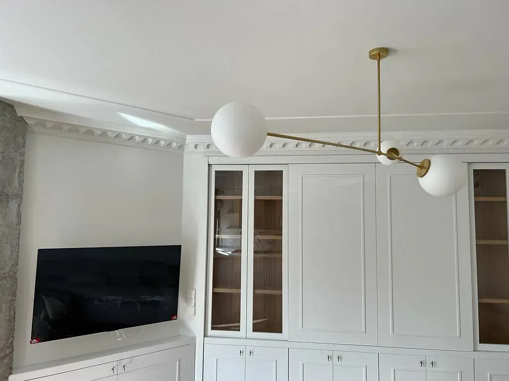 Una sala de estar con gabinetes blancos y una lámpara de techo colgando de ella.