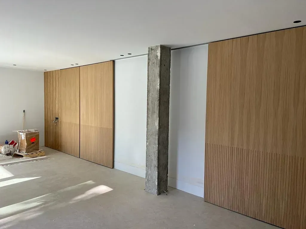 Una habitación con puertas corredizas de madera y una columna de hormigón.
