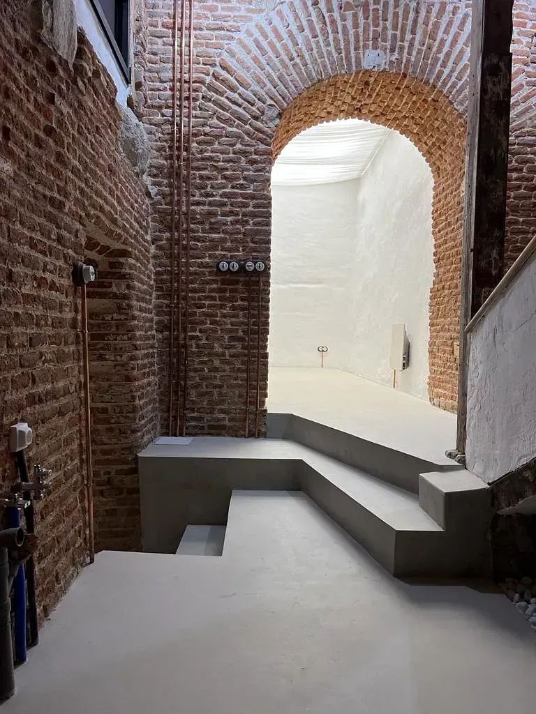 Hay una pared de ladrillos al fondo y una escalera en primer plano.