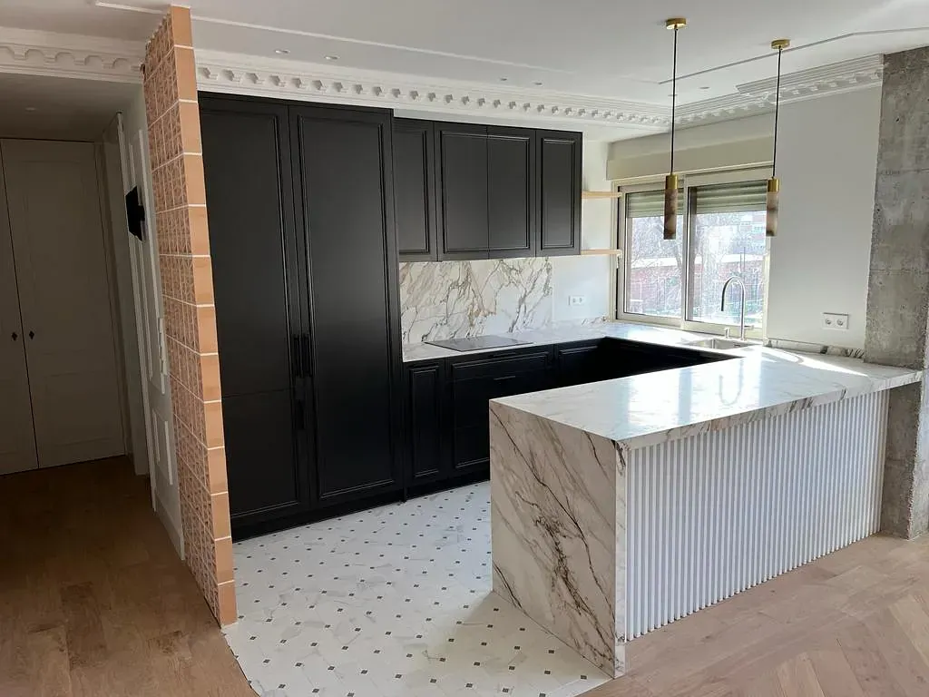 Una cocina con gabinetes negros y encimeras blancas.
