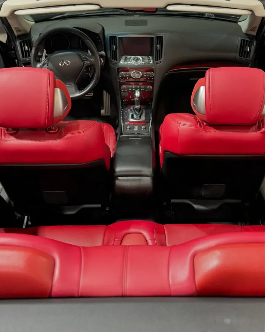 Interior de coche de cuero rojo con los asientos delanteros y traseros visibles, visto desde atrás hacia el salpicadero.