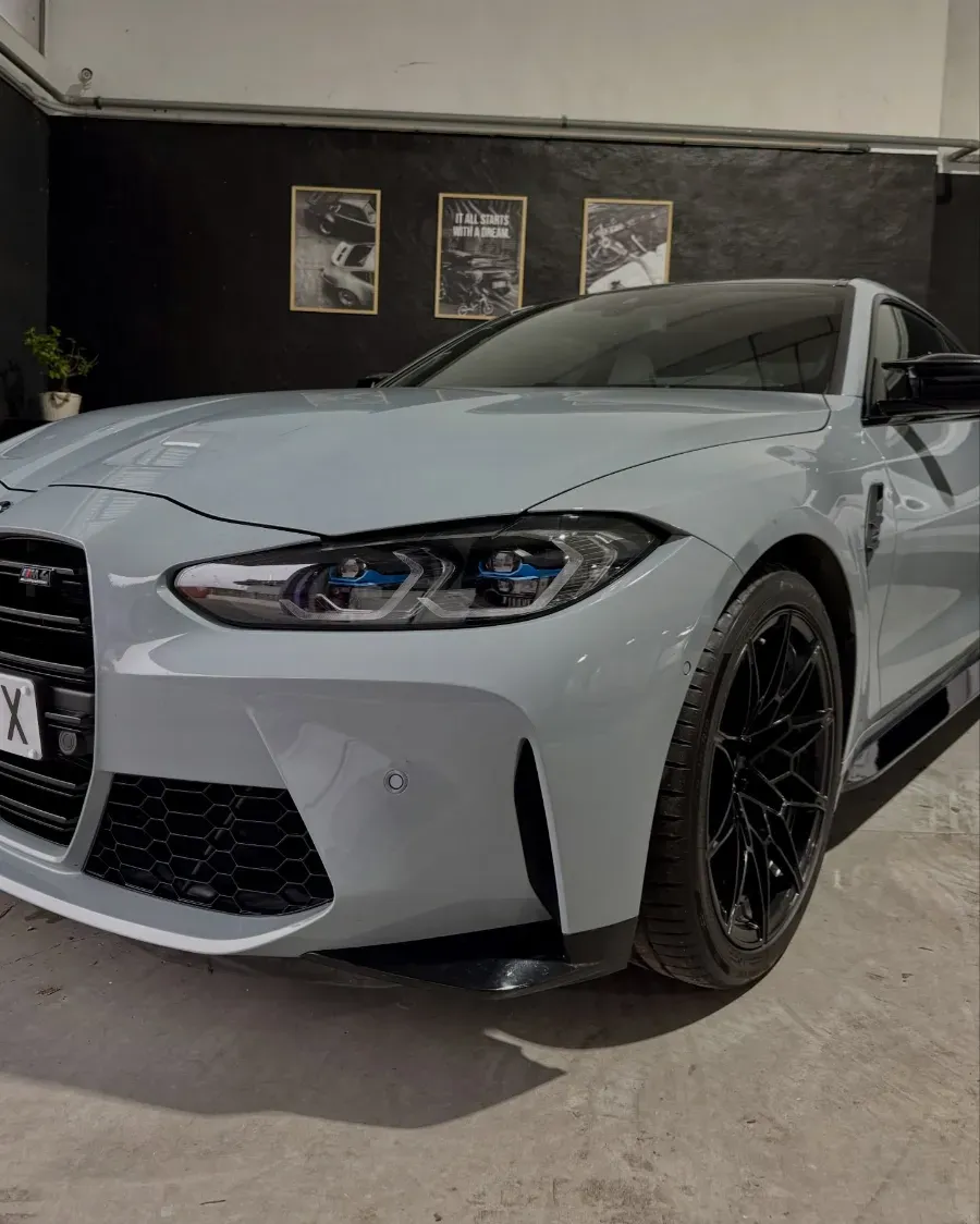 Coche deportivo gris claro con ruedas negras aparcado en el interior de un garaje.