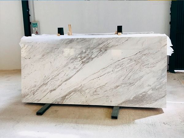 Una gran losa de mármol blanco reposa sobre un piso de madera.