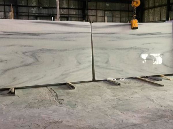 Una gran losa de mármol blanco reposa sobre un piso de concreto en un almacén.