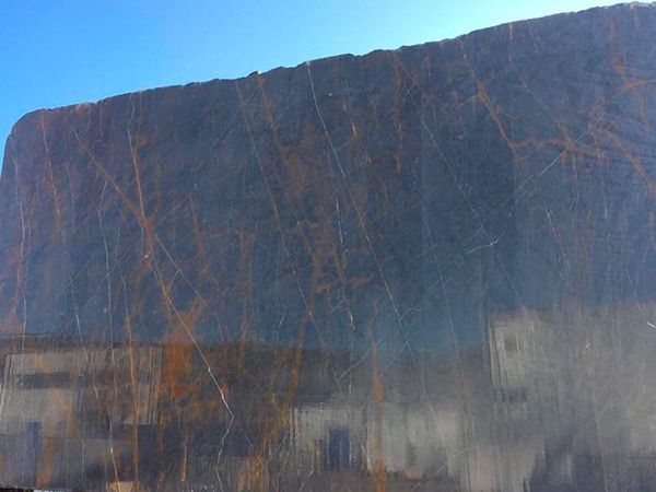 Una gran roca con un cielo azul al fondo.