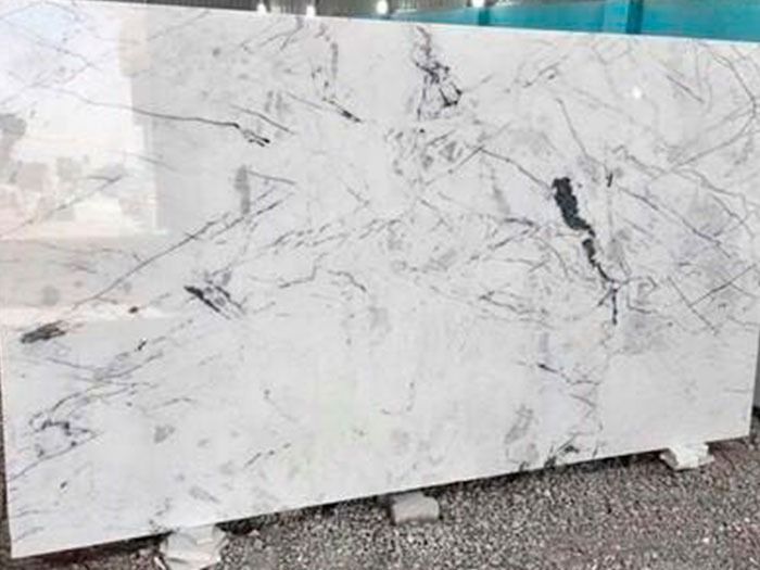 Una gran losa de mármol blanco reposa sobre una pila de grava.