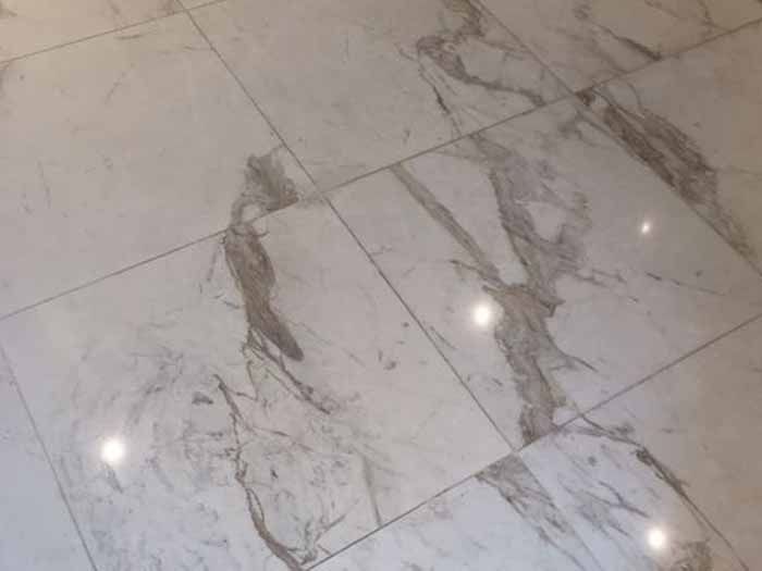 Un primer plano de un suelo de baldosas blancas con textura de mármol.