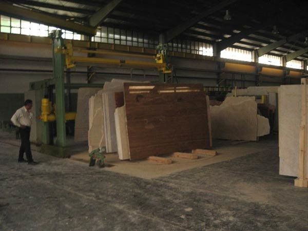Un hombre con una camisa blanca está parado en un almacén con muchos trozos de madera.