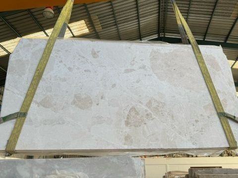 Una gran pieza de mármol blanco está siendo levantada por una grúa.