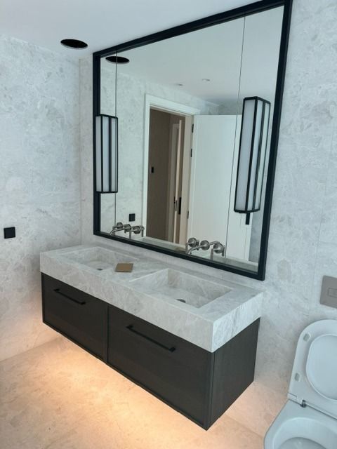 Un baño con dos lavabos y un espejo grande.