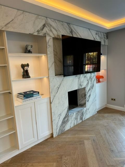 Una sala de estar con chimenea de mármol y TV de pantalla plana.