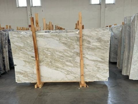 Una gran losa de mármol reposa sobre un soporte de madera en un almacén.