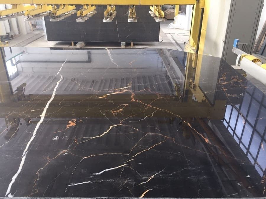 Se está cortando una losa de mármol negro y dorado en una fábrica.