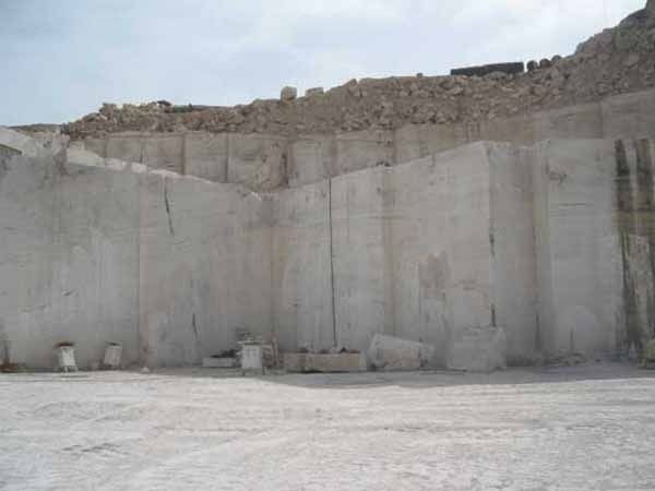 Un gran muro de hormigón en medio de un campo de tierra.