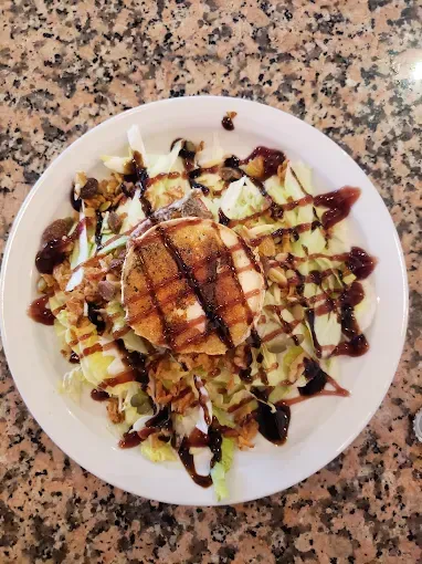 Ensalada con queso a la parrilla, rociada con glaseado balsámico, en un plato blanco.