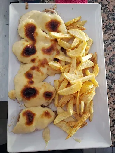 Plato de comida con carne cubierta con queso fundido y patatas fritas.