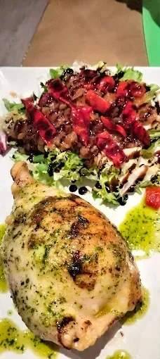 Plato de pollo con pesto, ensalada con pimientos y glaseado balsámico en un plato blanco.