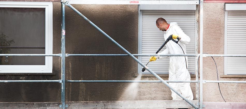 Homme qui nettoie à haute pression un mur noirci