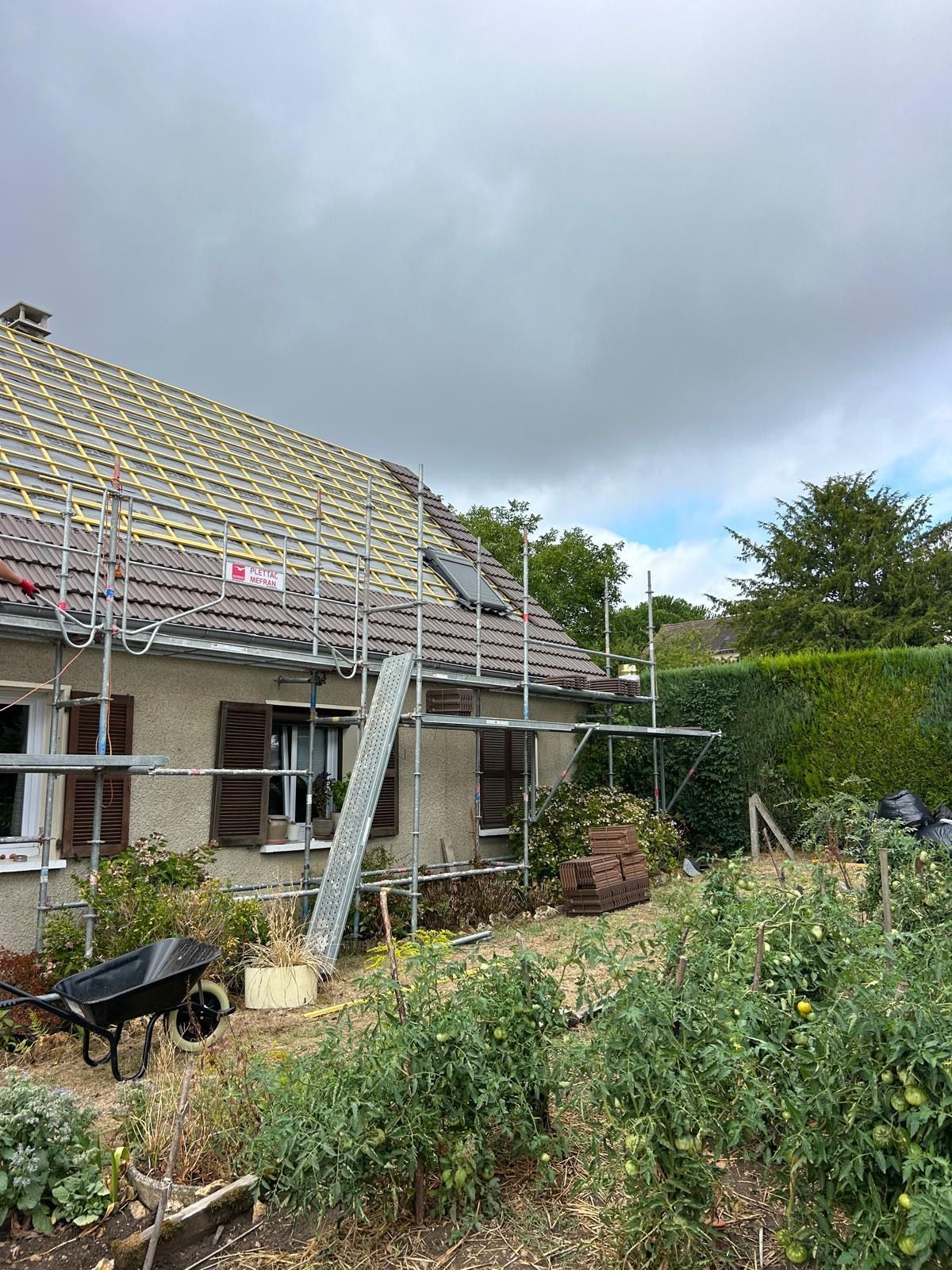 Maison dont le toit est en construction avec des échafaudages tout autour.
