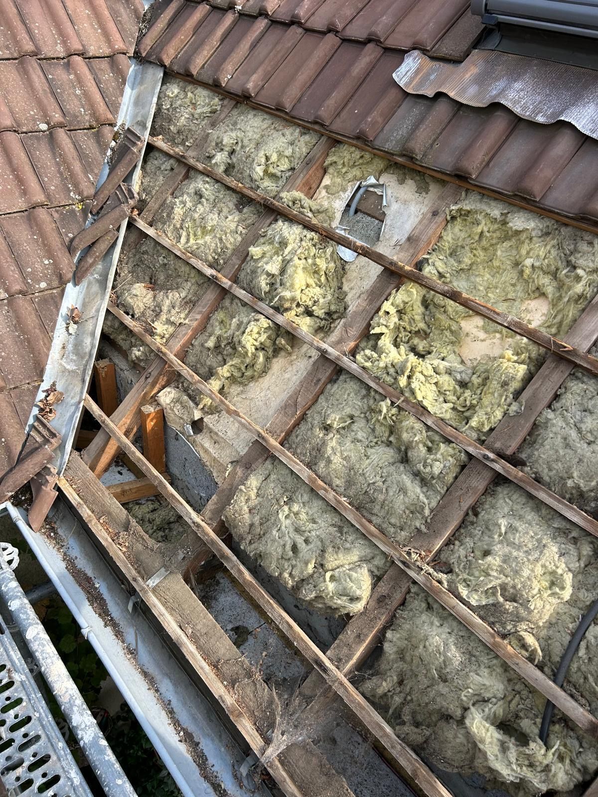 Réparation de toiture avec isolation apparente et liteaux en bois sous les tuiles rouges.