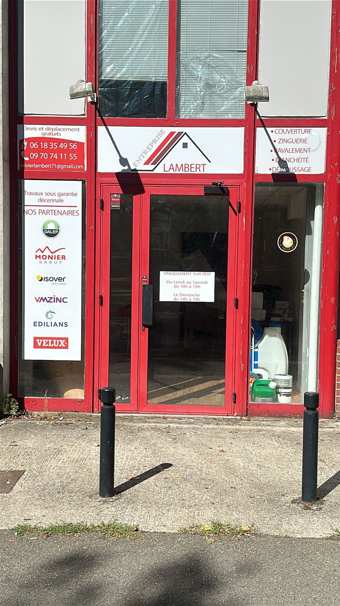 Façade rouge avec une porte vitrée et une enseigne blanche.