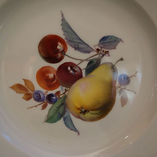 Ein weißer Teller mit einem gemalten Arrangement aus Kirschen, Blaubeeren und einer gelben Birne.