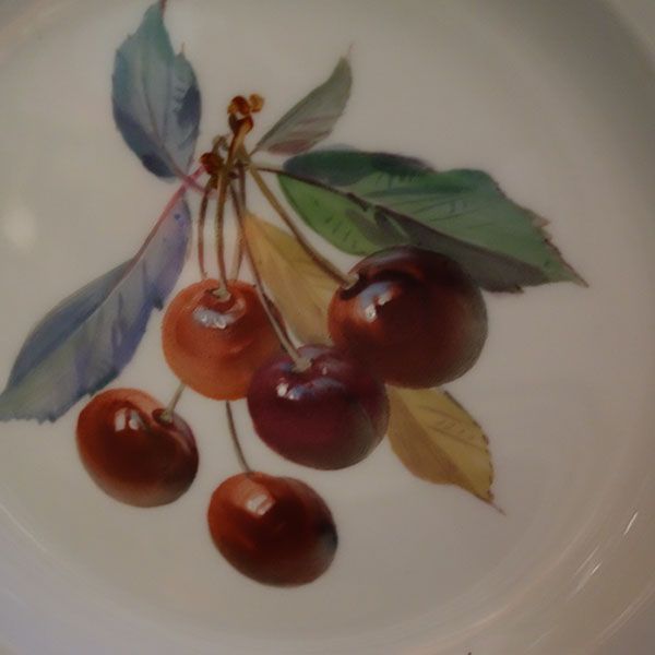 Weißer Tellers mit aufgemalten Kirschen.