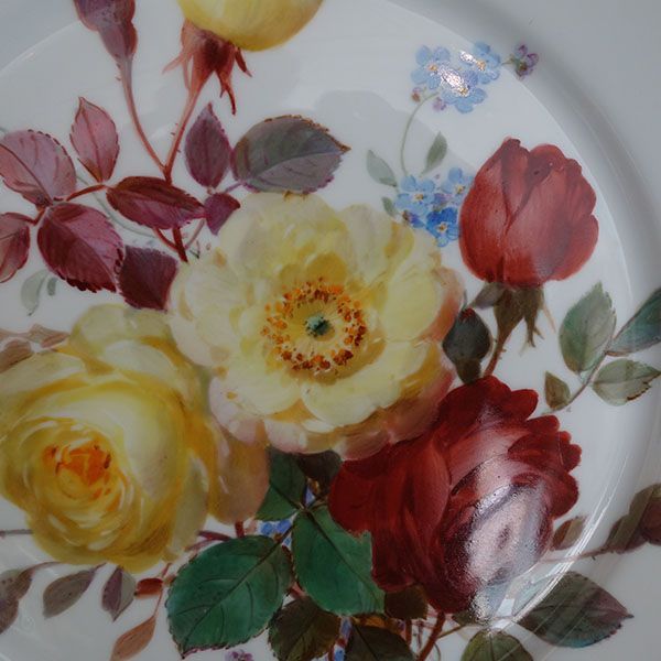 Teller mit floralem Muster aus gelben und roten Rosen und kleinen blauen Blumen.