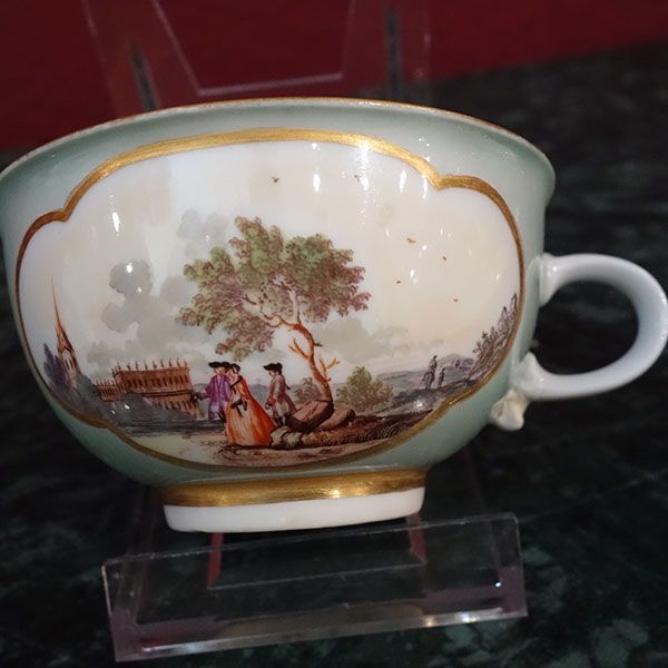 Antike Teetasse aus Porzellan, hellgrün mit Goldrand, malerisches Gemälde von Menschen neben einem Baum.
