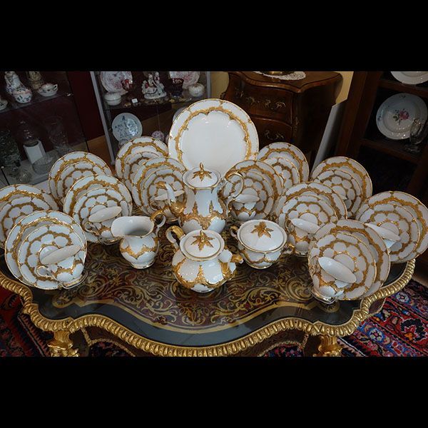 Ein formelles Porzellanservice mit Goldrand auf einem dekorativen Tisch.