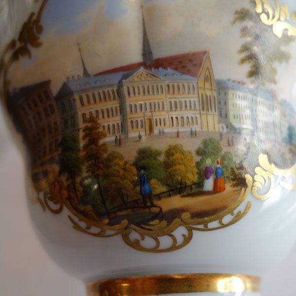 Detailliert bemalte Porzellantasse mit einem Gebäude und Menschen in einer parkähnlichen Umgebung.