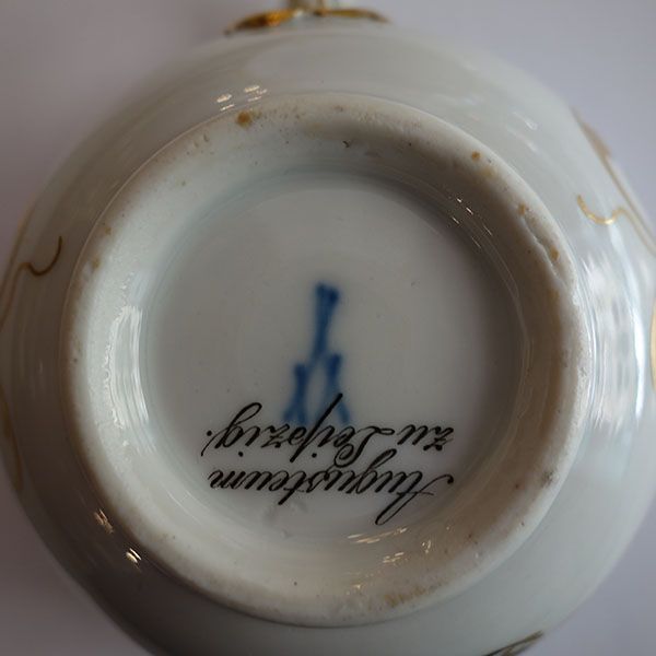 Unterseite eines weißen Porzellanobjekts mit blauer Marke und Text „Augusteum zu Leipzig“.
