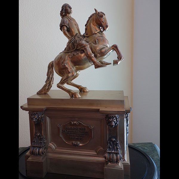 Bronzestatue eines Mannes auf einem sich aufbäumenden Pferd, auf einem verzierten Sockel mit einer Inschrift.